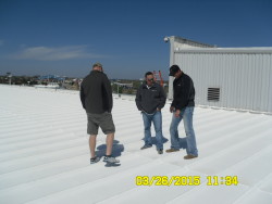 Three workers standing on commercial roof