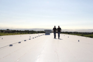 Two roofers inspecting a newly installed roofing system