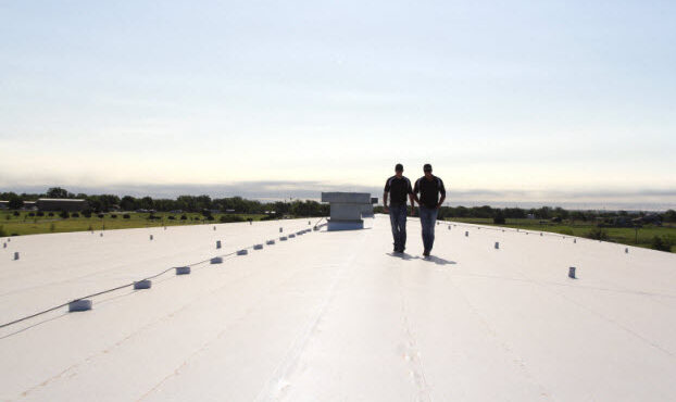 Two roofers inspecting a newly installed roofing system Single-Ply Roofing Benefits for Commercial Buildings