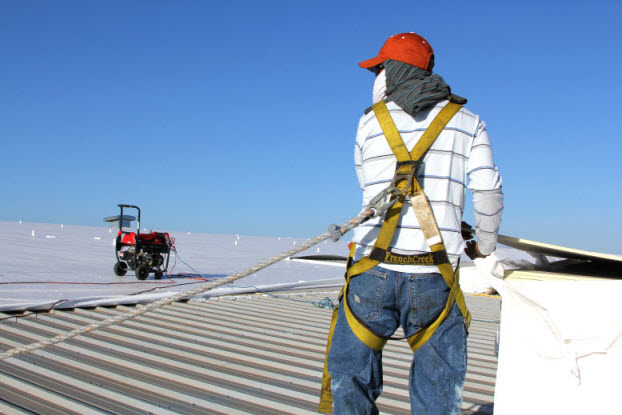 Worker wearing harness while installing commercial Duro-Last Roofing System