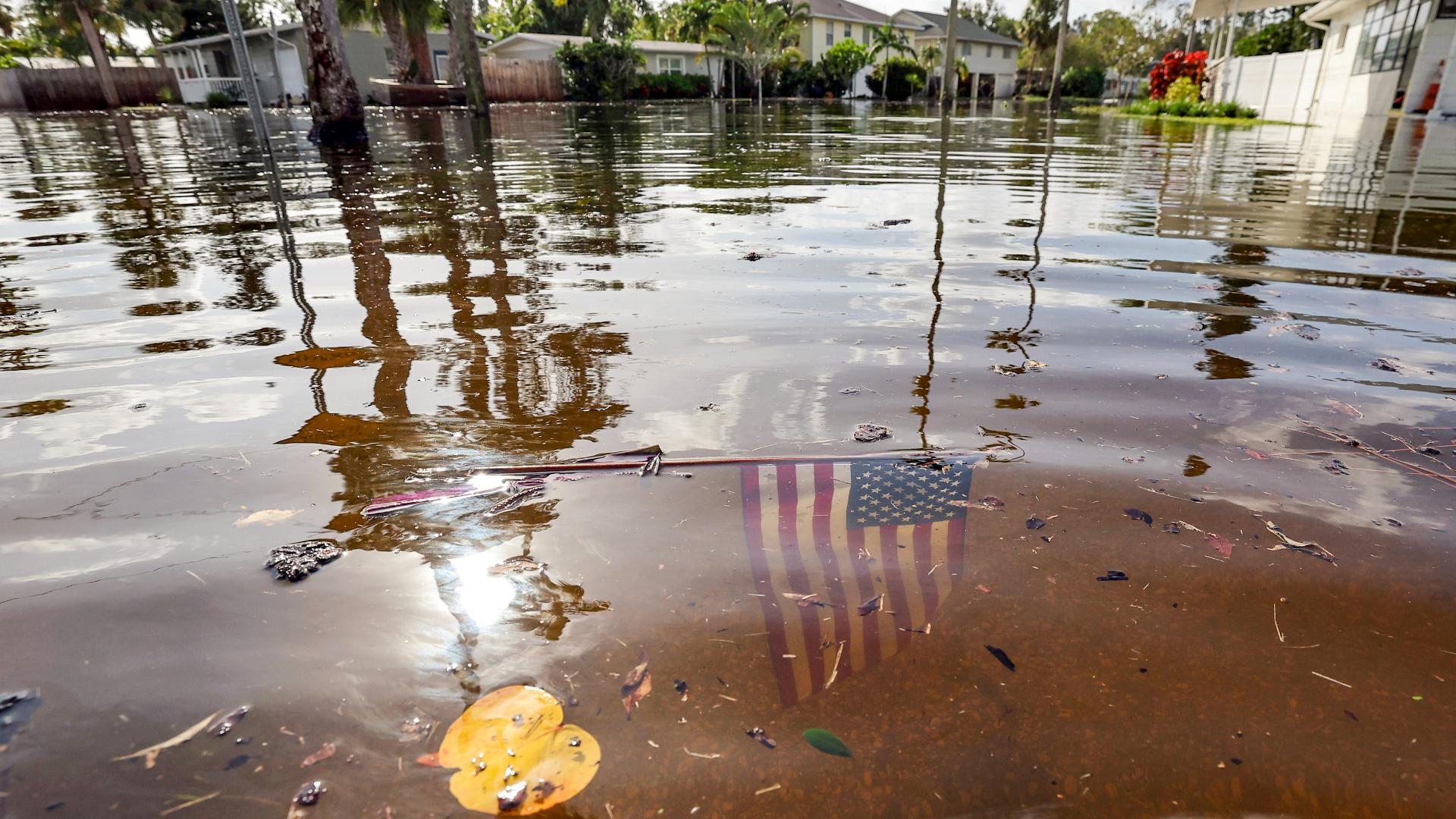 An American flag submerged in floodwaters after a hurricane in a residential neighborhood, symbolizing the aftermath of the storm.